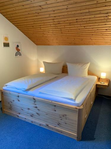 Cama grande de madera en habitación con techo de madera en Pension Elisa en Lechbruck