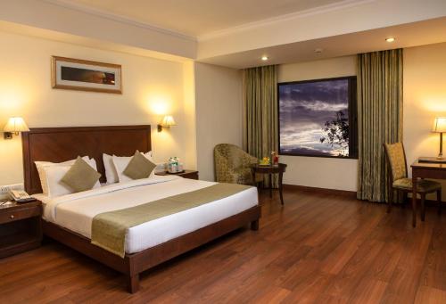 a hotel room with a large bed and a window at Le Lac Sarovar Portico- Ranchi in Rānchī