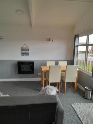 - un salon avec une table, des chaises et une cheminée dans l'établissement Perfect chalet to relax in k4, à Mablethorpe