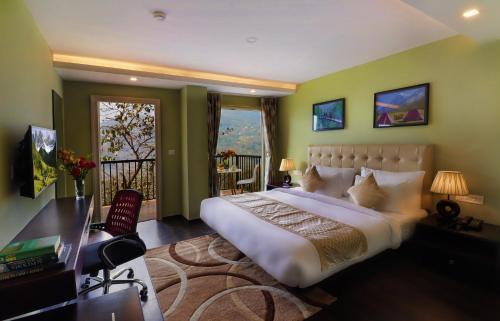 a bedroom with a large bed and a desk and a balcony at Five Gangtok in Gangtok