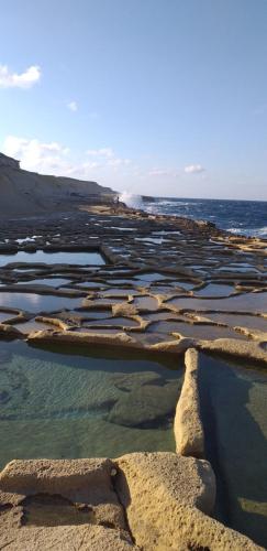 a group of rocks in the water near the ocean at MJ Farmhouse B&B in Xagħra
