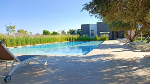 a swimming pool with lounge chairs next to a building at Villa Jardins D'Isa in Marrakech