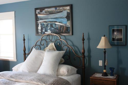 Eaglenest Manor Cowichan في دانكن: غرفة نوم زرقاء مع سرير مع وسائد بيضاء