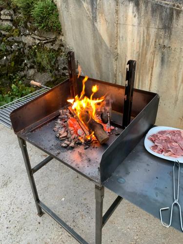 a barbecue grill with fire and a plate of meat at La Casa de la Colonia in Seira