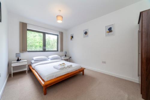 a white bedroom with a bed and a window at Modern 3BDR Flat w large balcony, Kentish Town in London