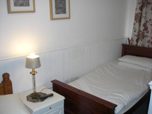 a bedroom with a bed and a lamp on a night stand at Lynebank House Hotel, Bed & Breakfast in Carlisle