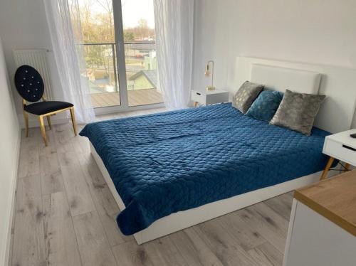 1 dormitorio con cama azul, silla y ventana en Apartament z basenem i sauną, en Dziwnów