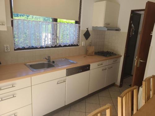 a kitchen with white cabinets and a sink and a window at Hello Zeeland - Vakantiehuis Zeester 66 in Breskens