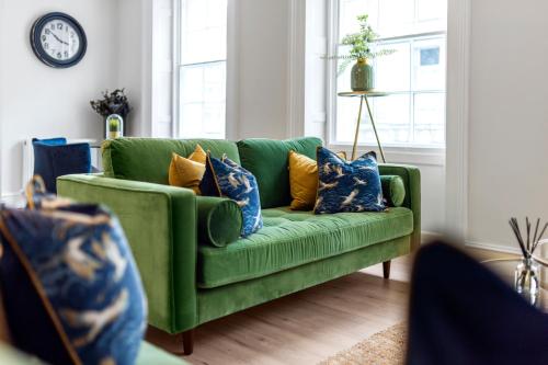 a green couch with blue and yellow pillows in a living room at Wilton House Belfast Serviced Apartments in Belfast