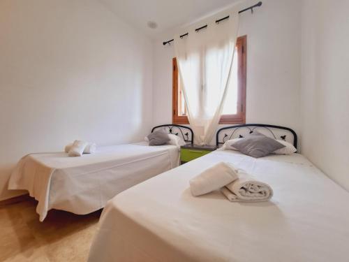 two beds in a room with white walls and a window at Apartamentos Turísticos La Carrajolilla in Chiclana de la Frontera