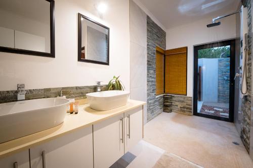 uma casa de banho com 2 lavatórios e um espelho em Gem In The Bush Lodge em Hoedspruit