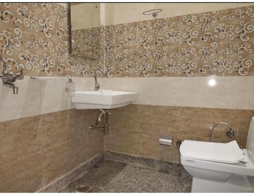 ein Badezimmer mit einem Waschbecken, einem WC und einem Spiegel in der Unterkunft Viren Plaza, Agra in Agra