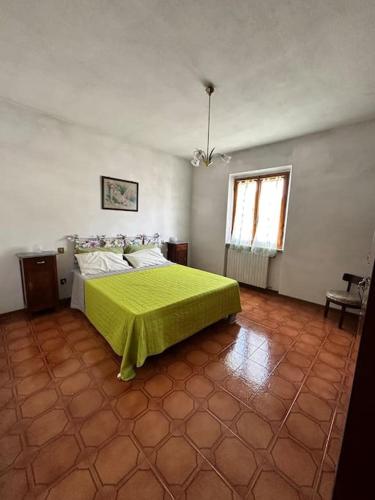 a bedroom with a bed with a green blanket on it at Appartamento Albatros in Ribolla