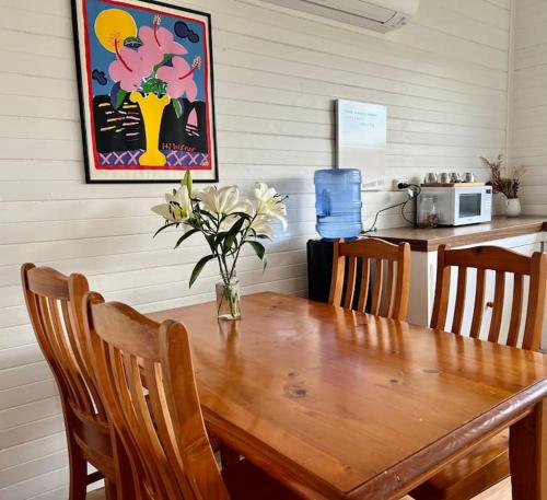 a dining room table with a vase of flowers on it at Primrose Cottage in Mandurama
