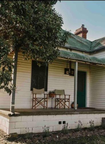 a porch of a house with two chairs and a table at Primrose Cottage in Mandurama