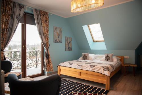 1 dormitorio con cama, ventana y silla en Folkowy Dworek SPA & Fun en Murzasichle