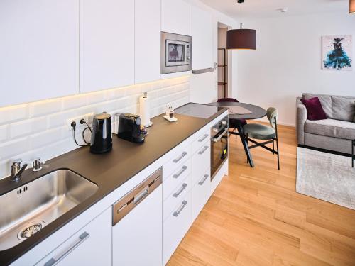 a kitchen with white cabinets and a sink and a table at MyFavorit Apartments - Spacious Apartments next to Puplic Transport U1 direct connection to Citycenter in Vienna