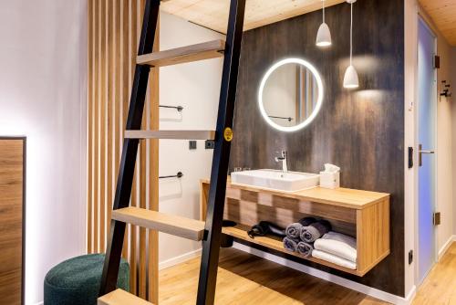 a loft bathroom with a sink and a mirror at BOLLWERK Lifestyle Hotel, automatisiertes Hotel mit Self Check In in Immenstadt im Allgäu