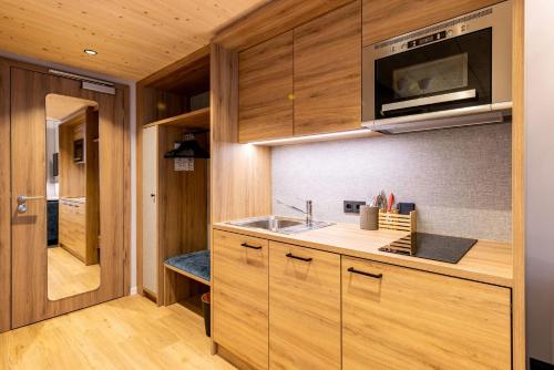 a kitchen with wooden cabinets and a sink at BOLLWERK Lifestyle Hotel, automatisiertes Hotel mit Self Check In in Immenstadt im Allgäu