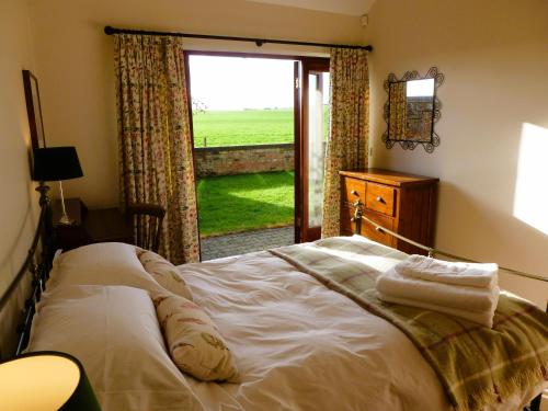 a bedroom with a bed and a window with a view at Smallthorns Barn in Market Harborough