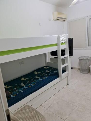 a white bunk bed in a room with a chair at Lovely Apt Close to Beach in Nahariyya