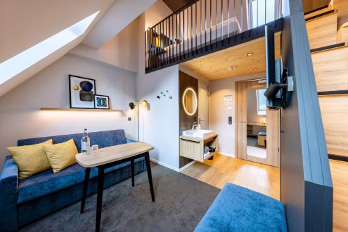 a living room with a blue couch and a table at BOLLWERK Lifestyle Hotel, automatisiertes Hotel mit Self Check In in Immenstadt im Allgäu