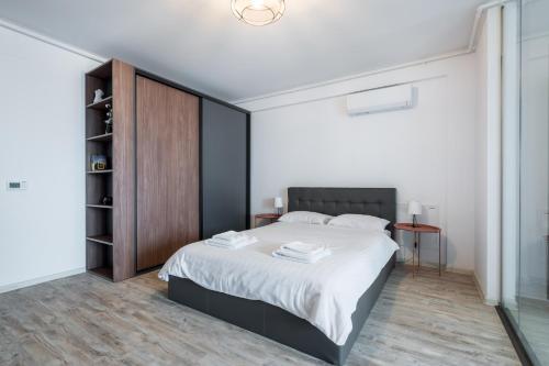 een slaapkamer met een groot bed en een houten kast bij Kondo studio I Roka Residence, Timpuri Noi in Boekarest