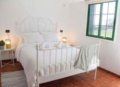 a white bed in a white bedroom with a window at La Macadamia in La Laguna