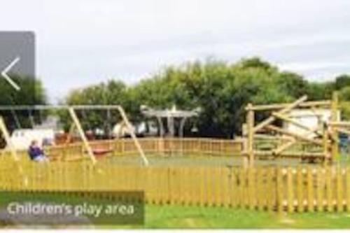 una zona de juegos para niños con columpios y un parque infantil en Beauview Brand New For 2023 Wi-Fi and Smart TV en Millom