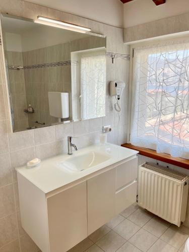a white bathroom with a sink and a mirror at Villa Carrera in Malcesine