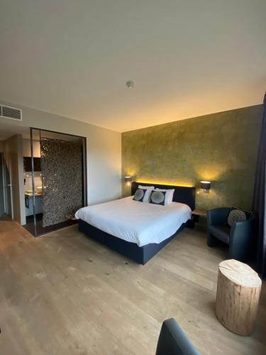 a hotel room with a bed and a chair at Hôtel WELLNESS EAU DE ROCHE Durbuy in Durbuy
