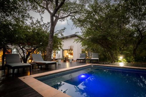 a swimming pool with chairs and a house at Gem In The Bush Lodge in Hoedspruit