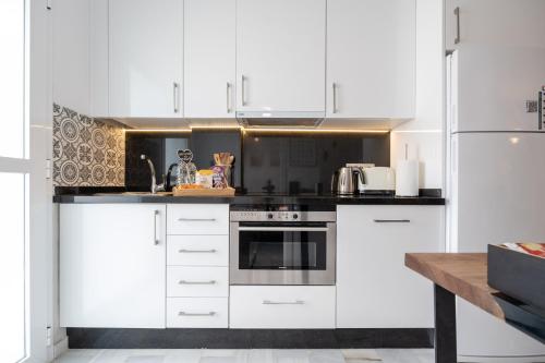 a white kitchen with white cabinets and a wooden table at Casa Hibiscus Marbella in Marbella