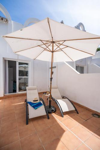 a large white umbrella and a chair and a table at Casa Hibiscus Marbella in Marbella