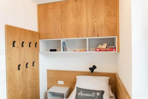 a small bedroom with a bed with wooden cabinets at Küsten Apartments Tannenhausen in Aurich