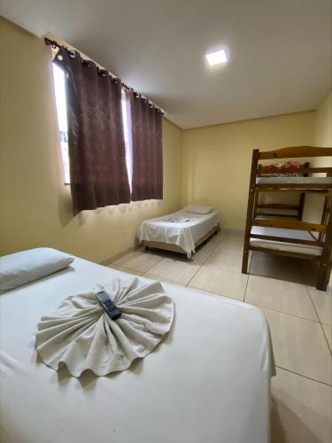 een kamer met 2 bedden en een stoel. bij Pousada Elita in Divinópolis
