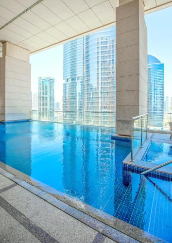a large swimming pool in a building with tall buildings at Lagom Vacation Homes 1 & 2 bedroom Apartment in Bonnington Tower, cluster J in Dubai