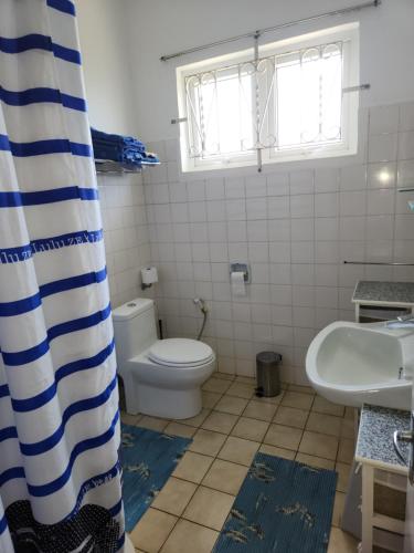 a bathroom with a toilet and a sink and a shower curtain at VILLA OASIS in Blue Bay