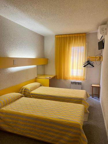 a hotel room with two beds and a window at Hostal - Restaurante Asador Esperanza in Huesca