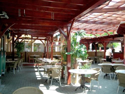 a restaurant with tables and chairs and a man in the background at Hotel Járja in Hajdúszoboszló