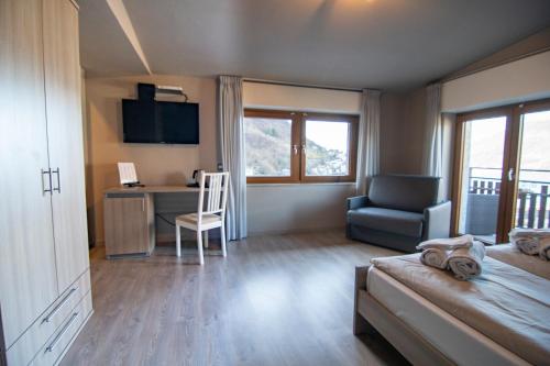 a bedroom with a bed and a desk and a chair at Hotel Saligari in Verceia