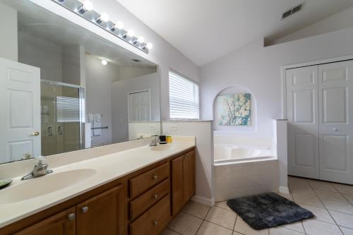 a bathroom with a sink and a tub and a mirror at 16150EGRET- Sun Chaser (S) in Orlando