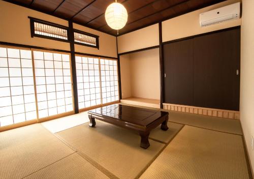 a room with a table in a room with windows at 予約制薪割りBBQ可能! 青の洞門から車で15分 l 四季折々の自然が楽しめる農泊古民家 鍋屋 in Sugihata