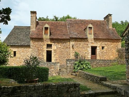 an old stone house with a stone wall at Chambres d'hôtes avec Piscine la Rossillonie in Beynac-et-Cazenac