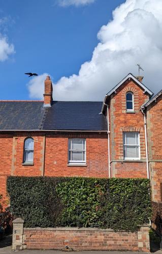 una casa di mattoni rossi con una siepe verde di 6 Park Terrace a Glastonbury