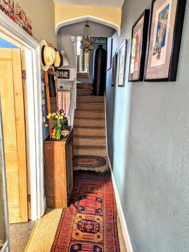 a hallway with a staircase with a rug on the floor at 6 Park Terrace in Glastonbury