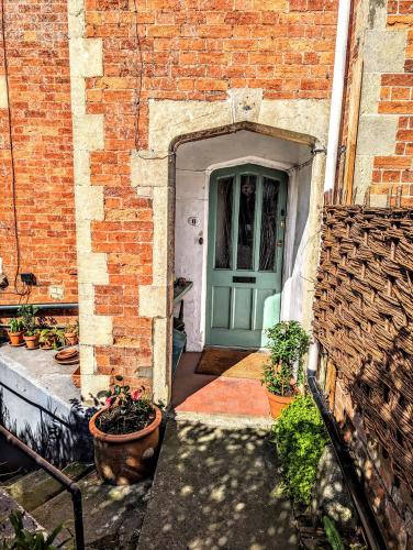 uma porta para um edifício de tijolos com vasos de plantas em 6 Park Terrace em Glastonbury