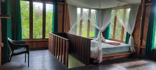 um quarto com uma cama num quarto com janelas em Sumatera tropical Tepikolam em Bohorok