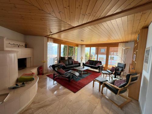 ein Wohnzimmer mit einem Sofa, Stühlen und einem Kamin in der Unterkunft Villa Nora in Faulensee