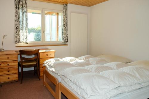 a bedroom with a bed and a desk and a window at Villa Nora in Faulensee